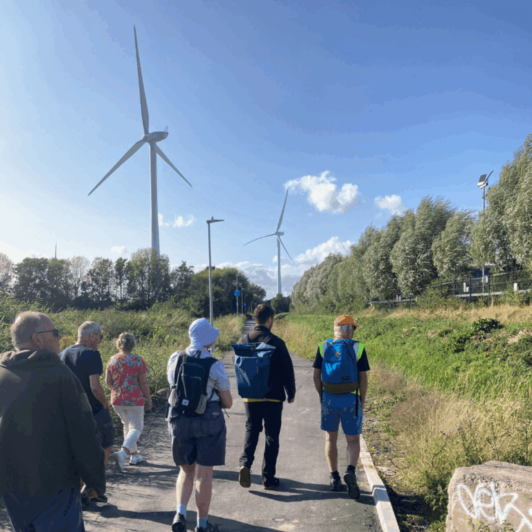 Group of people on wildlife walk with wind turbines in background