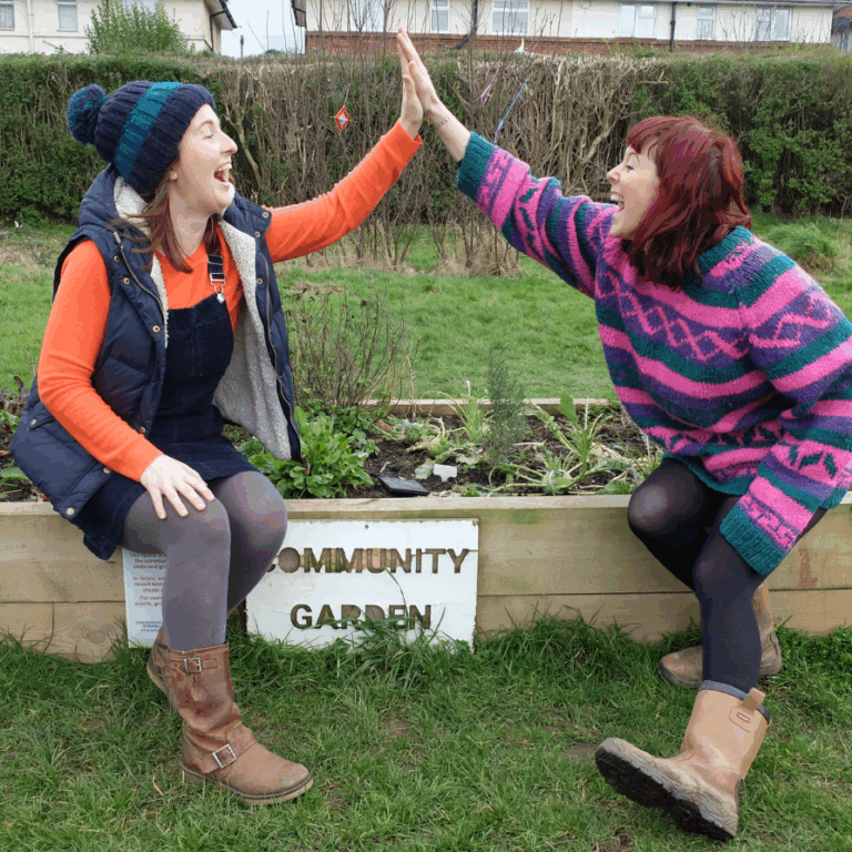 Two people giving each other a high five at a community garden