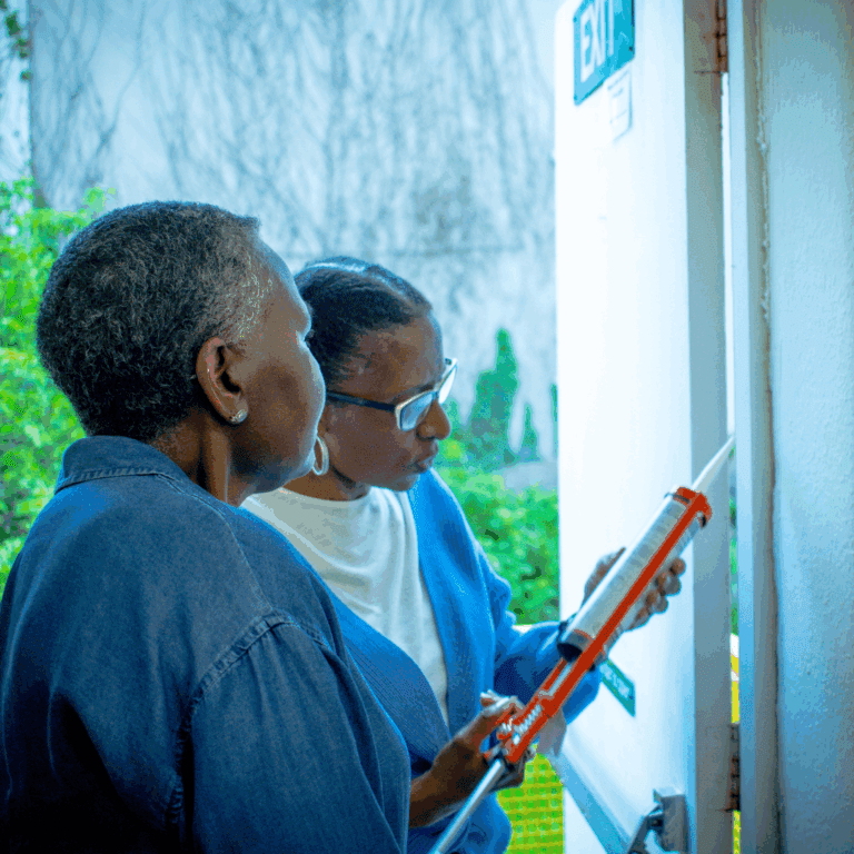 Two people trying out using a caulking gun