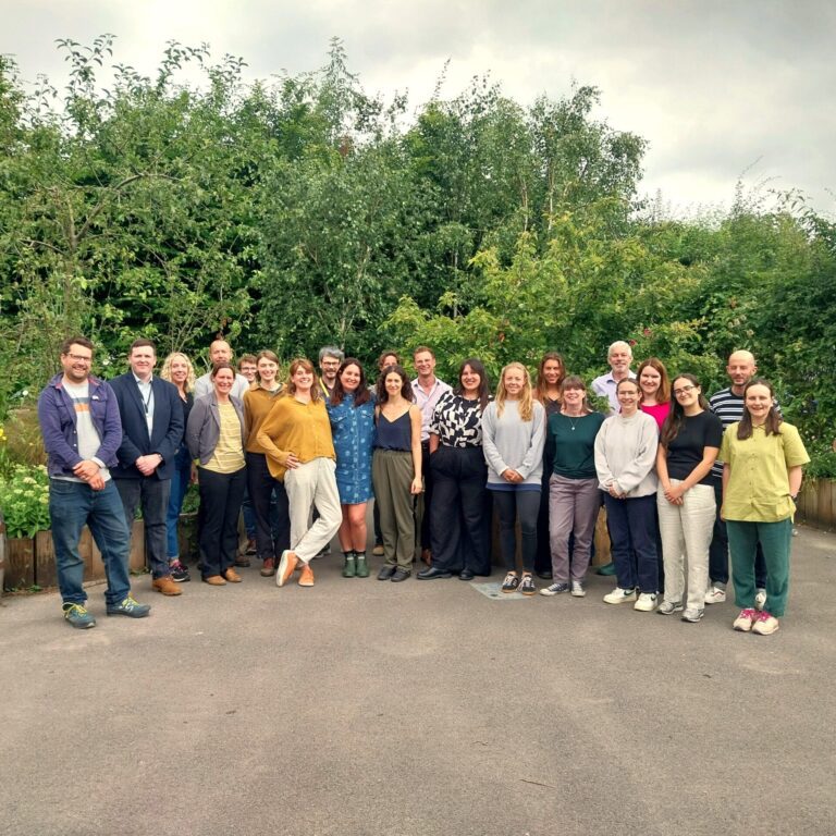 Group of people smiling at the camera, with trees in the background