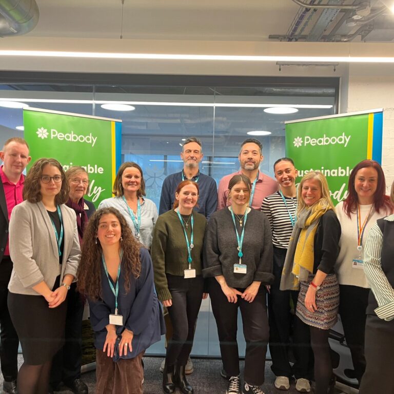 Group of people smiling standing in front of two green banners.