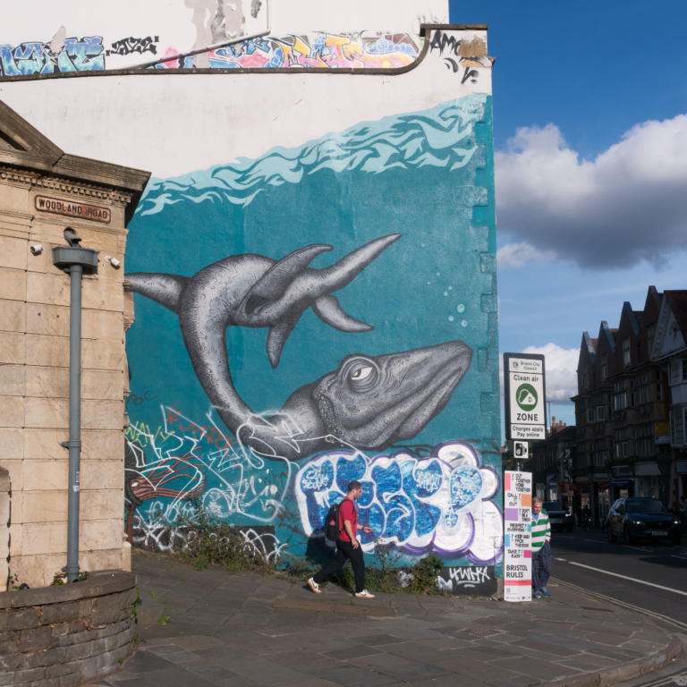Street scene with person walking past a building which has a large painting of a whale on it